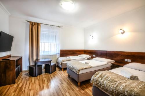 a room with three beds and a flat screen tv at Noclegi Europa in Bolesławiec