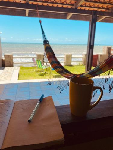 a book and a pen on a table with a hammock at Casa Mar Poesia - Taiba in Taíba