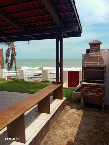 a bench under a pavilion with the beach in the background at Casa Mar Poesia - Taiba in Taíba