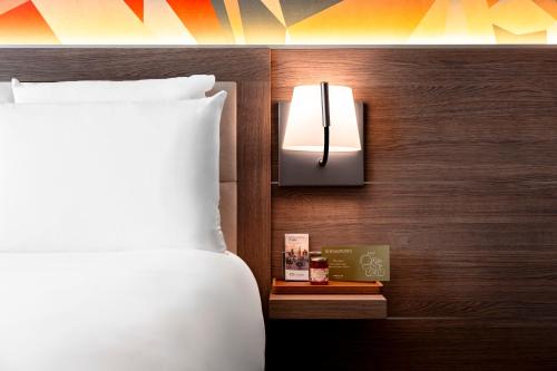 a bedroom with a bed and a lamp on a wall at Mercure Bayeux Omaha Beach in Port-en-Bessin-Huppain