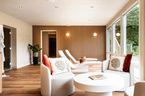 a living room with white chairs and a table at Mercure Bayeux Omaha Beach in Port-en-Bessin-Huppain