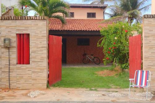 a house with a red fence and a chair at Casa Mar Poesia - Taiba in Taíba