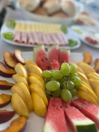 a plate of fruit with grapes and watermelon at LiEl Holiday in Vlorë