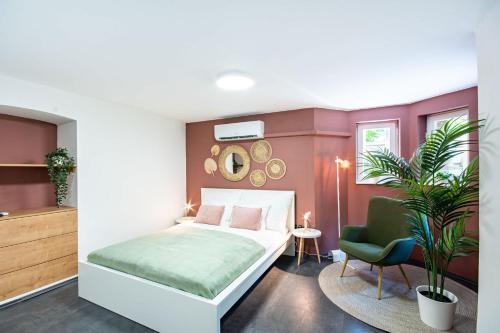 a bedroom with a bed and a chair and a plant at Central - Green - Stylish - Quiet Sleep in Debrecen