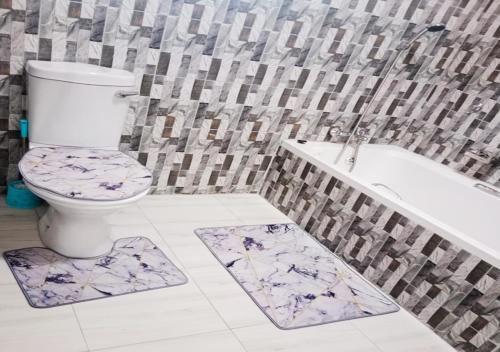 a bathroom with a toilet and a tub and mats at MC One Stop Road Lounge Hotel in Xai-Xai