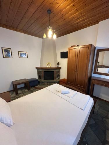 a bedroom with a large white bed and a fireplace at Φιλυρέα Apartments - Room 2 in Zagora