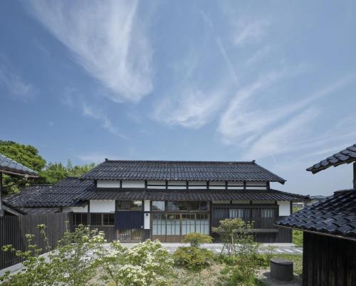 an external view of a house with a black roof at 佐渡古民家ステイ さどまり 泉の家 in Sado