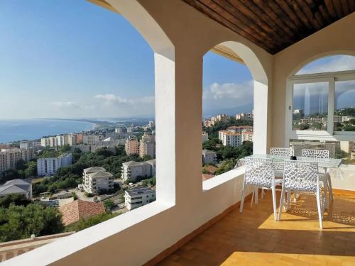 a balcony with a table and chairs looking out at the city at Appartement Vue Mer à Bastia, terrasse et piscine privée. in Bastia