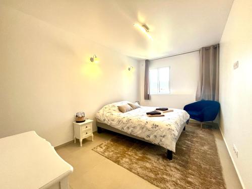 a small bedroom with a bed and a blue chair at Cosy village Home with Horizon in Bagnols-en-Forêt