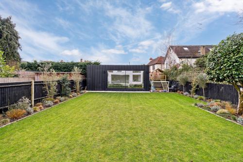 a garden with a large lawn in front of a house at Glade House in Marlow