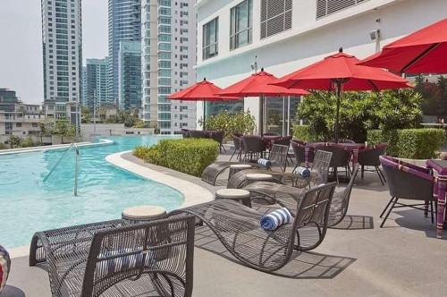 a pool with tables and chairs and red umbrellas at The hotel residences at Acqua in Manila