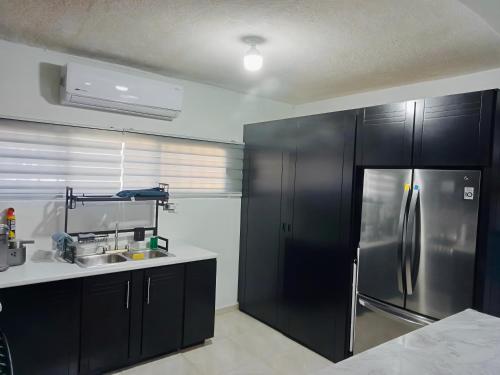 a kitchen with black cabinets and a stainless steel refrigerator at Puerto San Carlos Bay House & Tours -1st Floor- in San Carlos