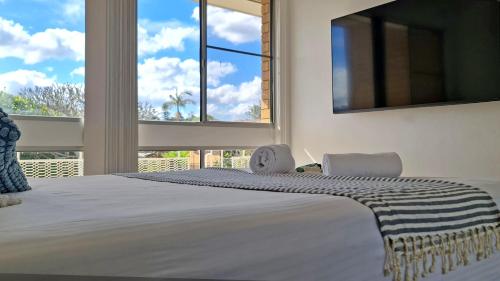 a bedroom with a large bed with two chairs and a window at 85 on First - Sawtell Apartments in Sawtell