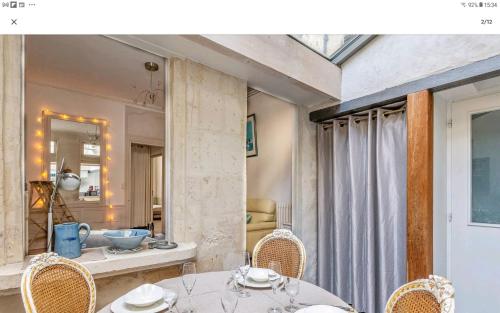 une salle à manger avec une table, des chaises et un miroir dans l'établissement L'atypique, au centre ville pour 4 à 5 personnes, à La Rochelle