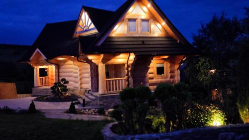 a house with lights on the front of it at night at Wood House in Nowy Targ