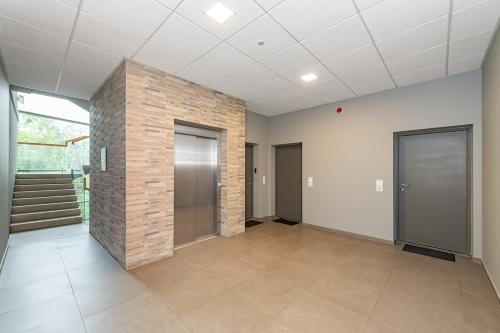 an empty room with a brick wall and doors at Sun Sonata Apartments 3 in Druskininkai