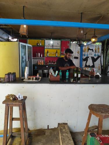 a man standing behind a counter in a bar at Arambol Residensea in Pernem
