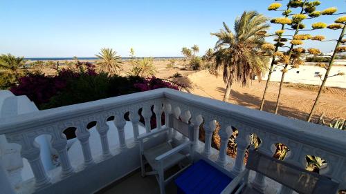 a balcony with a blue bench and the beach at maison d hôte rêve de désert jerba in Al Ḩaddādah