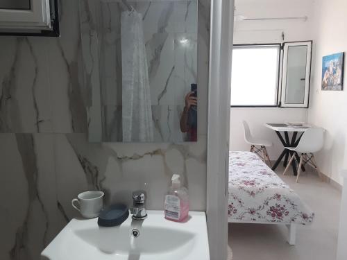 a person taking a picture of a bathroom with a sink at studio 1 Georgina in Mourteri