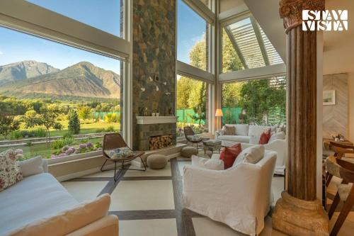 a living room with a large window with a view of mountains at StayVista at The Nestled North with Bonfire, lawn in Srinagar