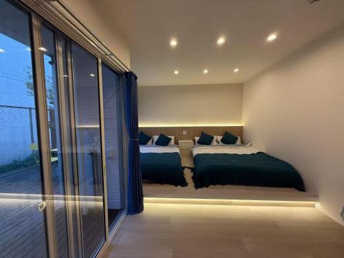 a bedroom with two beds and a balcony at アロハ鎌倉 in Kamakura