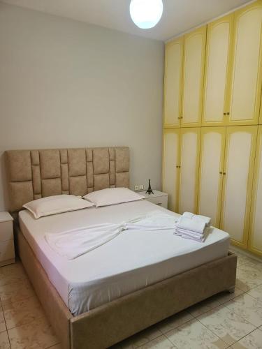 a bedroom with a large bed and yellow cabinets at Leva's Apartments in Sarandë