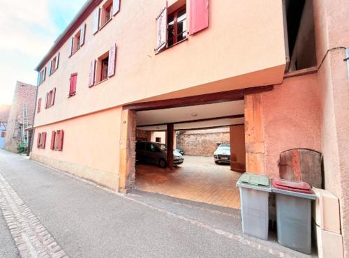 a building with a garage with cars parked in it at Authentique Alsacien - coeur historique de Rouffach in Rouffach
