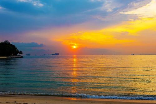 a sunset on the beach with the sun setting at Tiny Away Escape at Lazarus - 1980 in Singapore