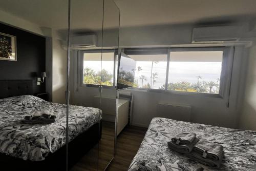 - une chambre avec 2 lits et un mur en verre dans l'établissement Comfortable apartment with exceptional sea view, à Vallauris