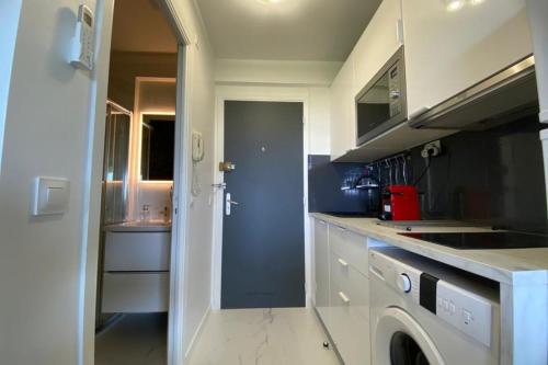 une cuisine avec des armoires blanches et une laveuse et une sécheuse dans l'établissement Comfortable apartment with exceptional sea view, à Vallauris