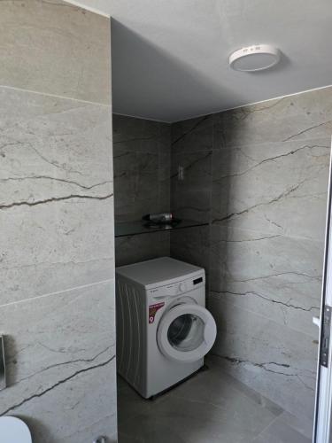 a bathroom with a washing machine and a stone wall at Leva's Apartments in Sarandë
