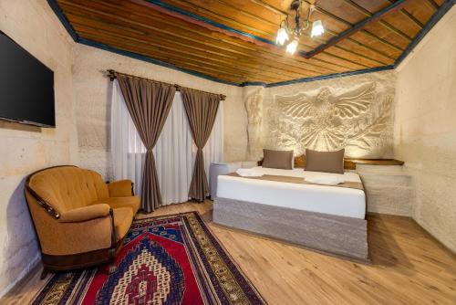 a bedroom with a bed and a chair at Kayatas Cave Suites in Goreme
