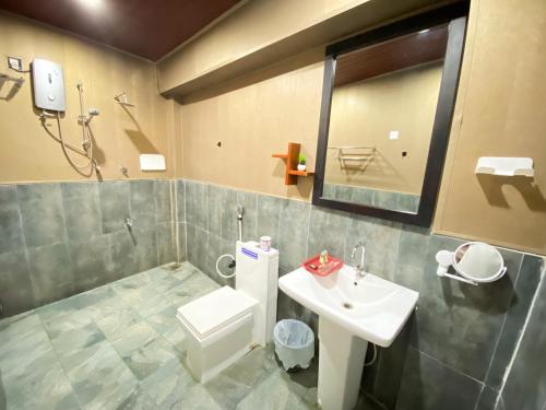 a bathroom with a sink and a toilet and a mirror at Coco Palm Villa and Cabanas in Tangalle