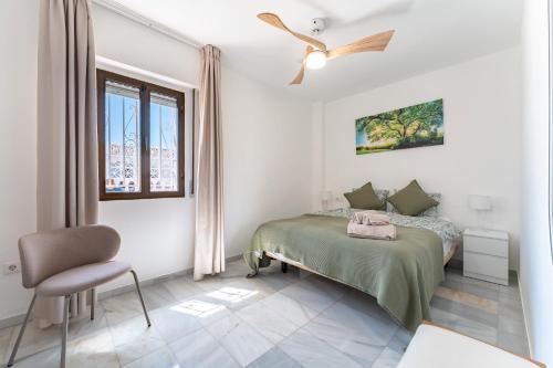 a white bedroom with a bed and a chair at La Riviera in La Cala de Mijas