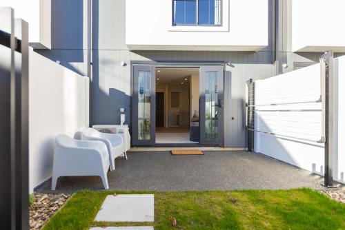 a patio with two white chairs and a building at Luxury CBD Townhouse 3 Bed 2 Bath With Car Park in Christchurch