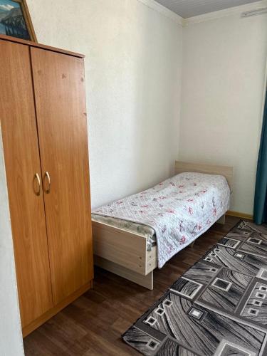 a small bedroom with a bed and a cabinet at Green Forest guest house in Ivano-Alekseyevka