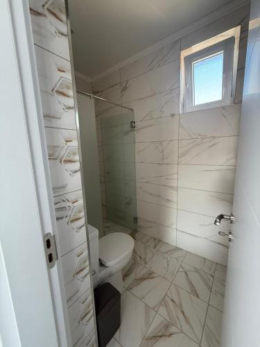 a white bathroom with a toilet and a window at Aurum Villas Smokinya Beach 4 in Sozopol