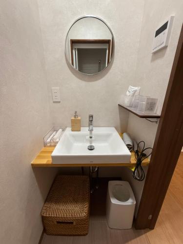 a bathroom with a sink and a mirror at Guesthouseあいみ in Amami