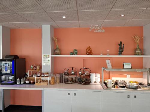 - une cuisine avec des murs orange et un comptoir blanc dans l'établissement ibis Styles Marseille Aéroport, à Vitrolles