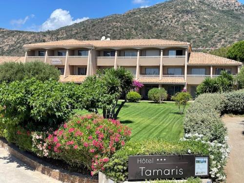 a large building with a sign in front of it at Hôtel Tamaris in Le Lavandou