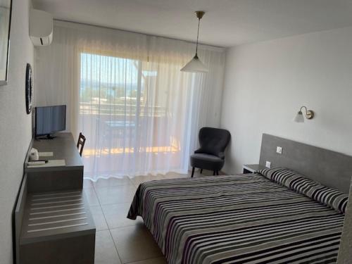 a bedroom with a bed and a desk and a chair at Hôtel Tamaris in Le Lavandou