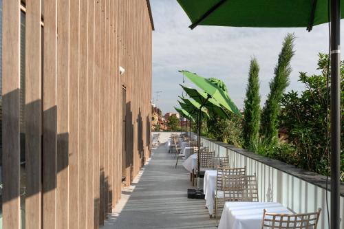 a row of tables and chairs on a sidewalk with an umbrella at Hotel Calimala Milano in Milan