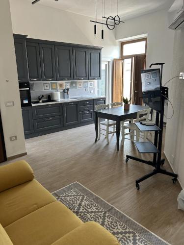 ein Wohnzimmer mit Tisch und Küche in der Unterkunft Domu e Cannonau in Nuoro