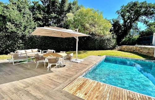une piscine avec un parasol, une table et des chaises dans l'établissement La Villa Blanche, à Cavalaire-sur-Mer