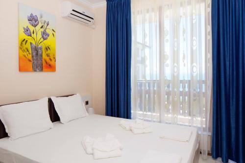 a bedroom with a white bed and blue curtains at Mars Apartments in Tryavna Beach Complex in Sveti Vlas