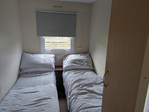 two beds in a small room with a window at The Hidden Gem in Galloway Forrest in Balminnoch