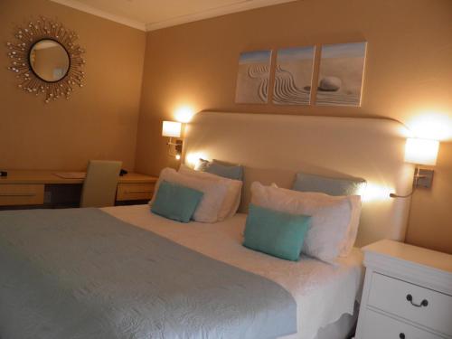 a bedroom with a bed with blue and white pillows at Homestay Travel Guest House in Roodepoort