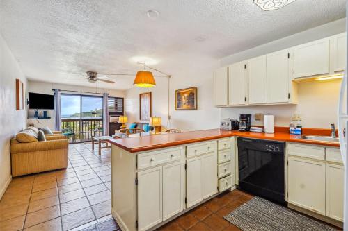 a kitchen with white cabinets and a living room at Beachfront Bungalow Walk to Ocean & Restaurants in Lihue