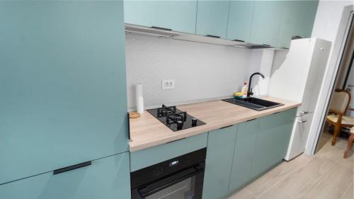 een keuken met blauwe kasten en een kookplaat oven bij Sarah Home in Boekarest