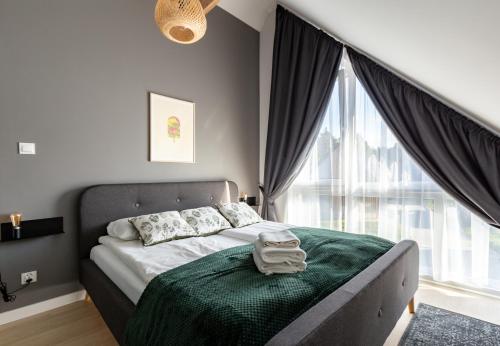 a bedroom with a bed with a green blanket and a window at Willa 27 Lakeside Retreat Łączyno by BookingHost in Łączyno